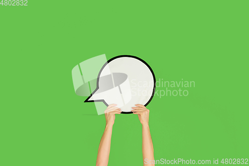 Image of Hands holding the sign of comment on green studio background