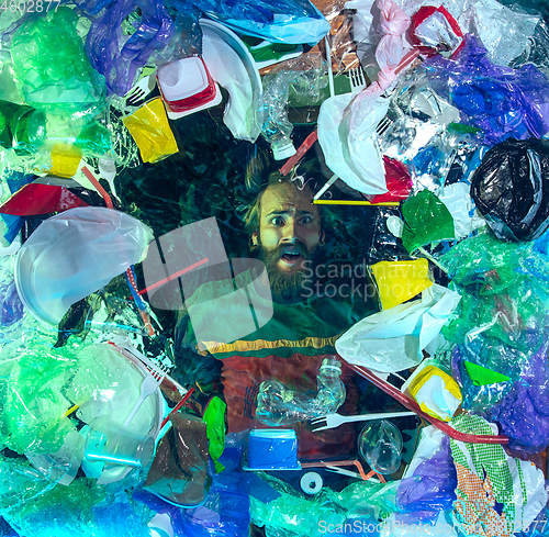 Image of Man drowning in ocean water under plastic recipients pile, environment concept