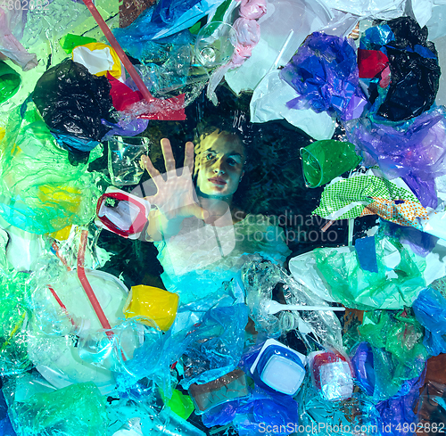 Image of Woman drowning in ocean water under plastic recipients pile, environment concept