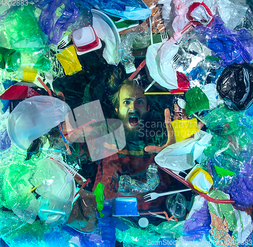 Image of Man drowning in ocean water under plastic recipients pile, environment concept