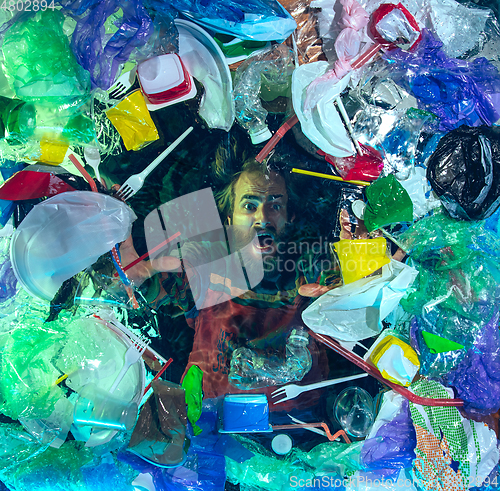 Image of Man drowning in ocean water under plastic recipients pile, environment concept