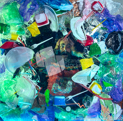 Image of Man drowning in ocean water under plastic recipients pile, environment concept