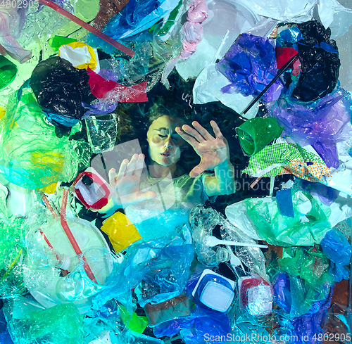 Image of Woman drowning in ocean water under plastic recipients pile, environment concept