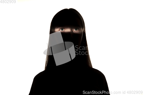 Image of Dramatic portrait of a girl in the dark on white studio background.