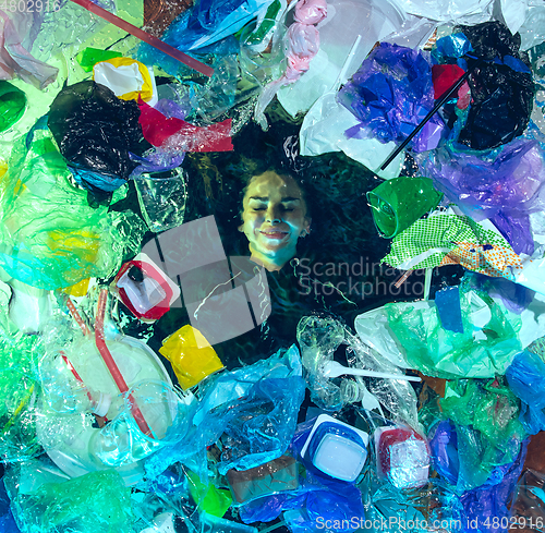 Image of Woman drowning in ocean water under plastic recipients pile, environment concept