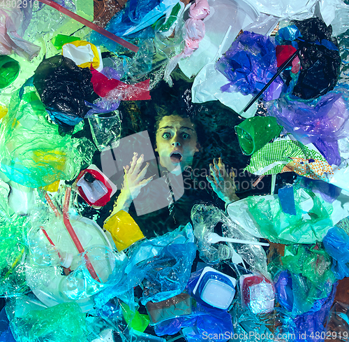 Image of Woman drowning in ocean water under plastic recipients pile, environment concept