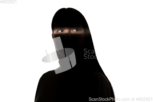 Image of Dramatic portrait of a girl in the dark on white studio background.