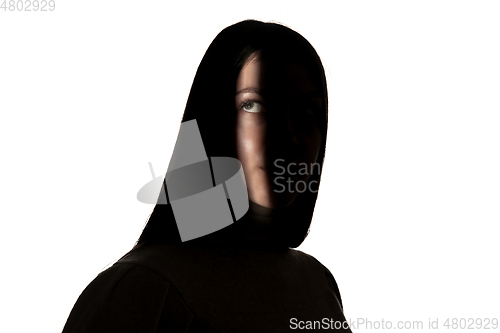 Image of Dramatic portrait of a girl in the dark on white studio background.