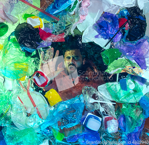 Image of Man drowning in ocean water under plastic recipients pile, environment concept
