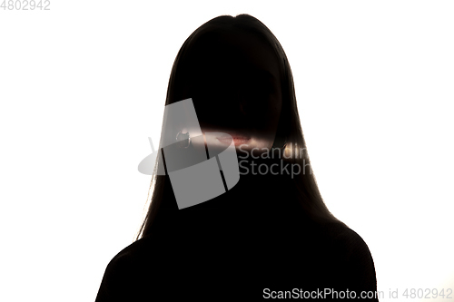 Image of Dramatic portrait of a girl in the dark on white studio background.