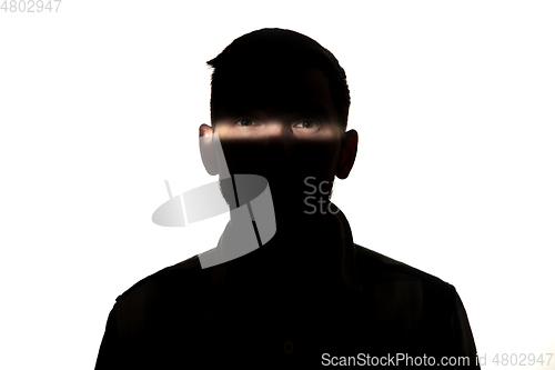 Image of Dramatic portrait of a man in the dark on white studio background.