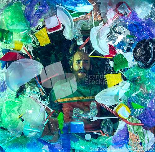 Image of Man drowning in ocean water under plastic recipients pile, environment concept