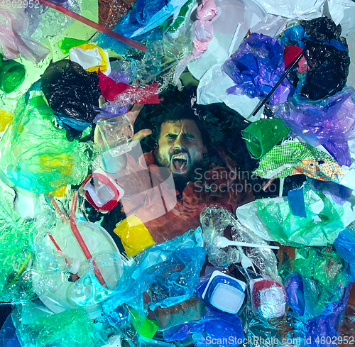 Image of Man drowning in ocean water under plastic recipients pile, environment concept