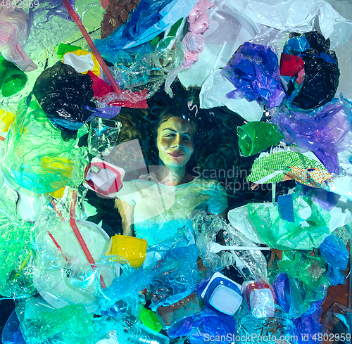 Image of Woman drowning in ocean water under plastic recipients pile, environment concept