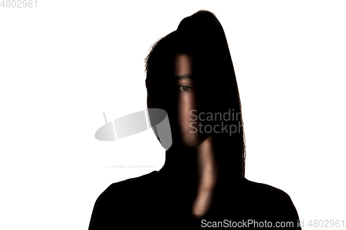 Image of Dramatic portrait of a girl in the dark on white studio background.