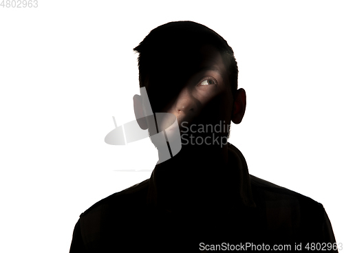 Image of Dramatic portrait of a man in the dark on white studio background.