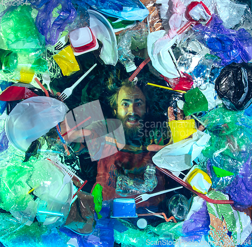 Image of Man drowning in ocean water under plastic recipients pile, environment concept