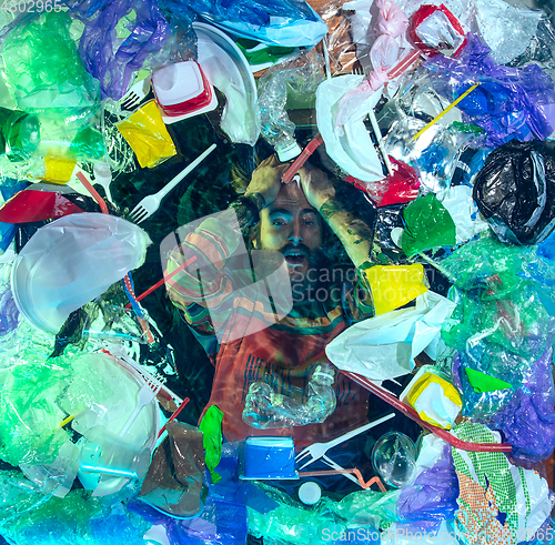 Image of Man drowning in ocean water under plastic recipients pile, environment concept