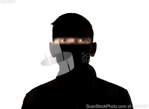 Image of Dramatic portrait of a man in the dark on white studio background.