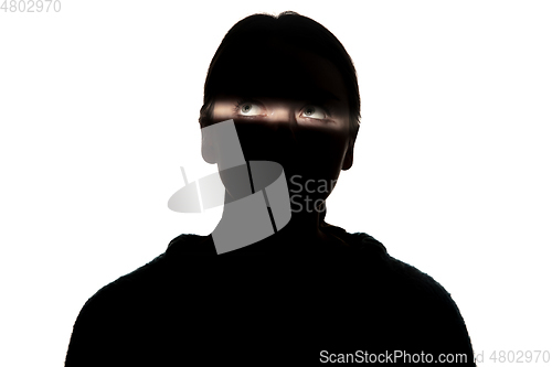 Image of Dramatic portrait of a girl in the dark on white studio background.