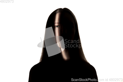 Image of Dramatic portrait of a girl in the dark on white studio background.