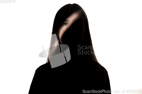 Image of Dramatic portrait of a girl in the dark on white studio background.