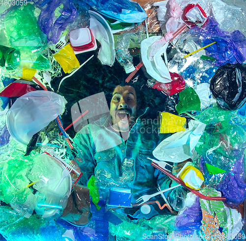 Image of Man drowning in ocean water under plastic recipients pile, environment concept