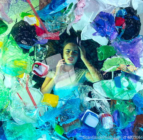 Image of Woman drowning in ocean water under plastic recipients pile, environment concept