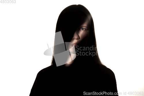 Image of Dramatic portrait of a girl in the dark on white studio background.