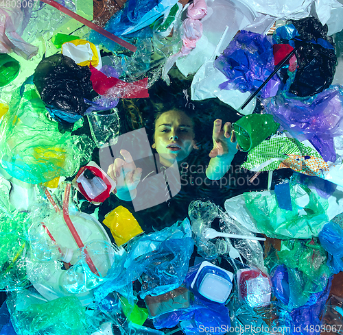 Image of Woman drowning in ocean water under plastic recipients pile, environment concept