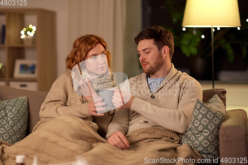 Image of sick young couple drinking hot tea at home