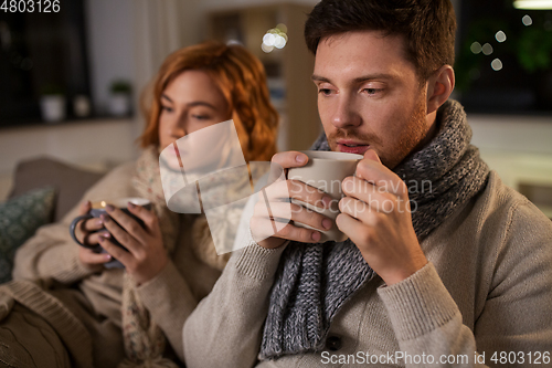 Image of sick young couple drinking hot tea at home