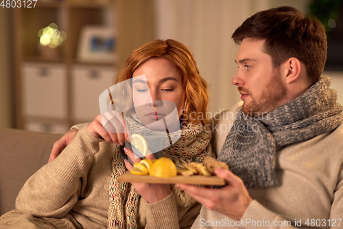 Image of sick young couple drinking tea with lemon at home