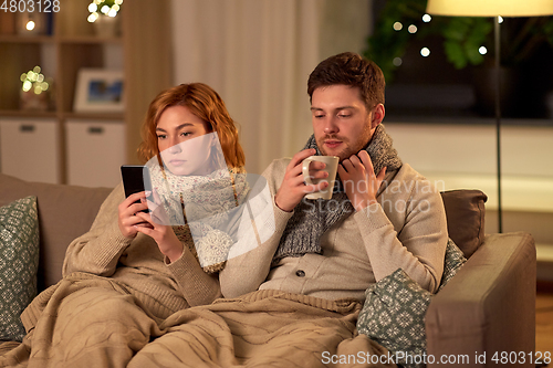 Image of sick young couple with smartphone at home