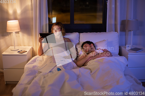 Image of woman with tablet computer working in bed at night