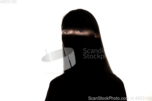 Image of Dramatic portrait of a girl in the dark on white studio background.