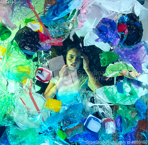 Image of Woman drowning in ocean water under plastic recipients pile, environment concept