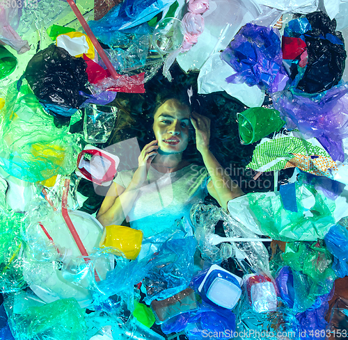 Image of Woman drowning in ocean water under plastic recipients pile, environment concept