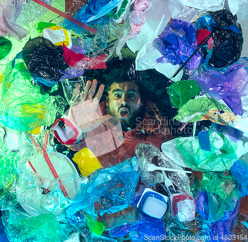 Image of Man drowning in ocean water under plastic recipients pile, environment concept