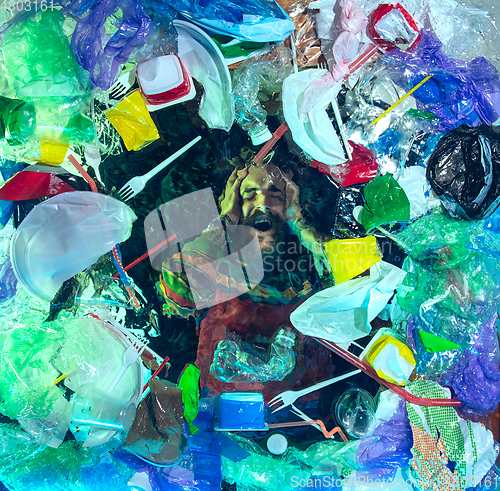 Image of Man drowning in ocean water under plastic recipients pile, environment concept