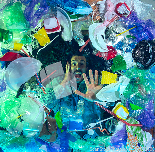 Image of Man drowning in ocean water under plastic recipients pile, environment concept