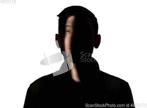 Image of Dramatic portrait of a man in the dark on white studio background.