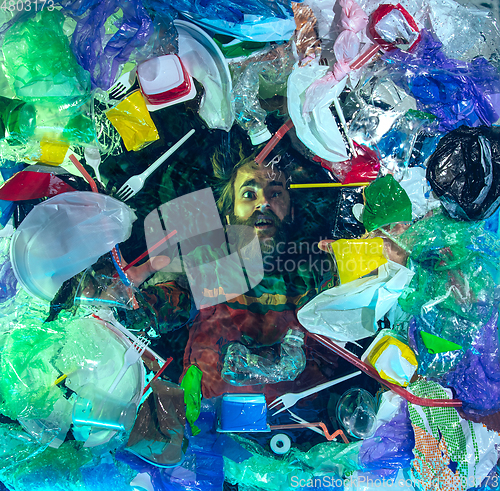 Image of Man drowning in ocean water under plastic recipients pile, environment concept