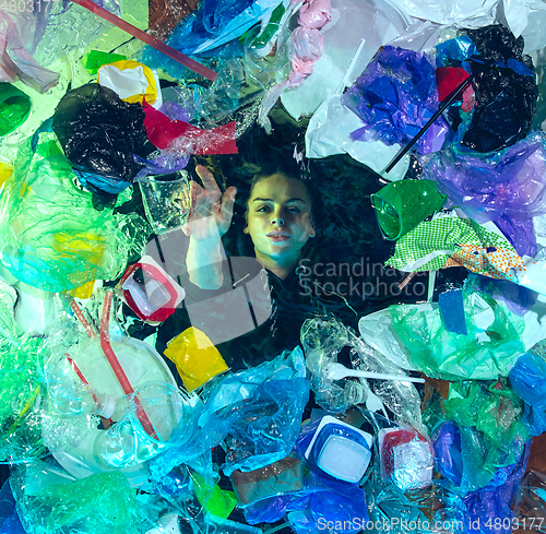 Image of Woman drowning in ocean water under plastic recipients pile, environment concept