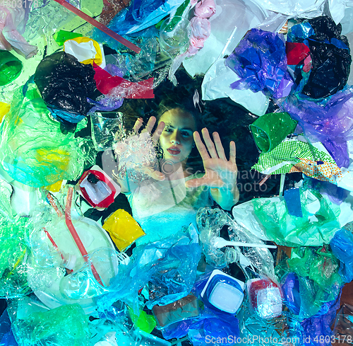 Image of Woman drowning in ocean water under plastic recipients pile, environment concept