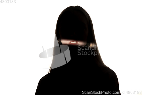 Image of Dramatic portrait of a girl in the dark on white studio background.