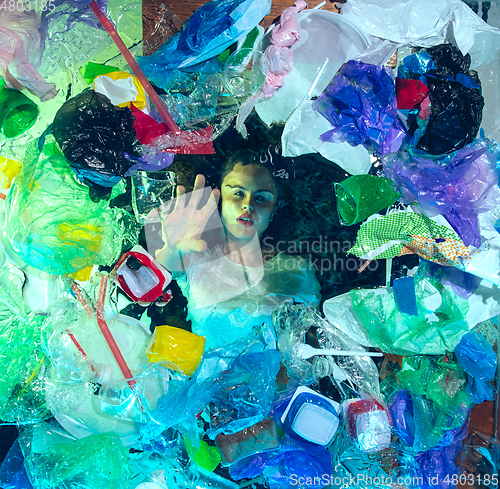 Image of Woman drowning in ocean water under plastic recipients pile, environment concept