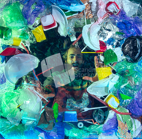 Image of Man drowning in ocean water under plastic recipients pile, environment concept