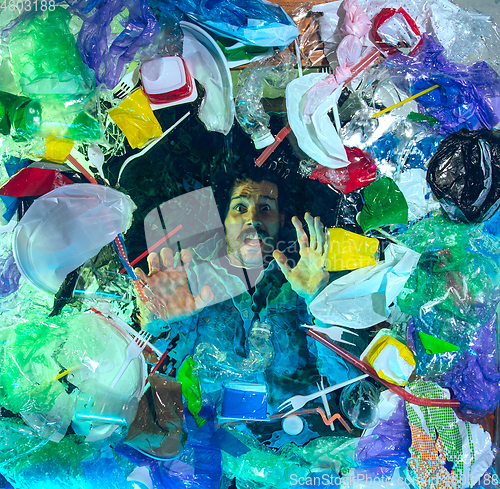 Image of Man drowning in ocean water under plastic recipients pile, environment concept