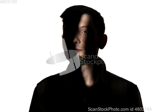 Image of Dramatic portrait of a man in the dark on white studio background.